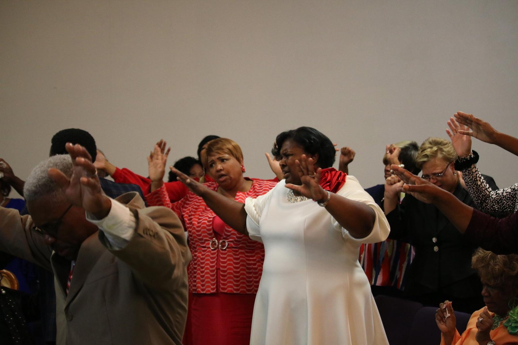 Christ Holy Temple congregation worshipping with hands raised